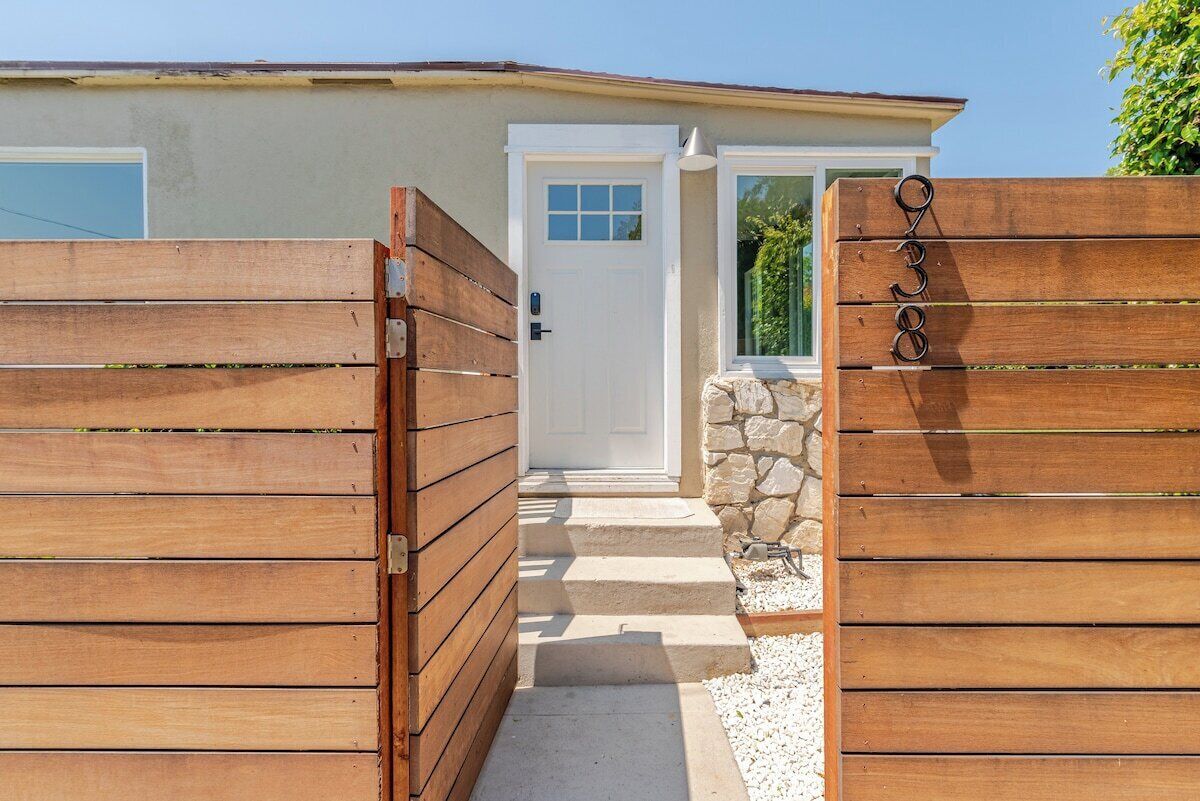 A gated entrance to a building with a stone wall and steps leading to a door.