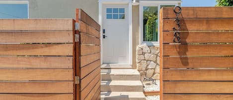 A gated entrance to a building with a stone wall and steps leading to a door.