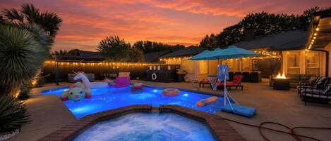 Een achtertuin met een zwembad, een jacuzzi en een terras.