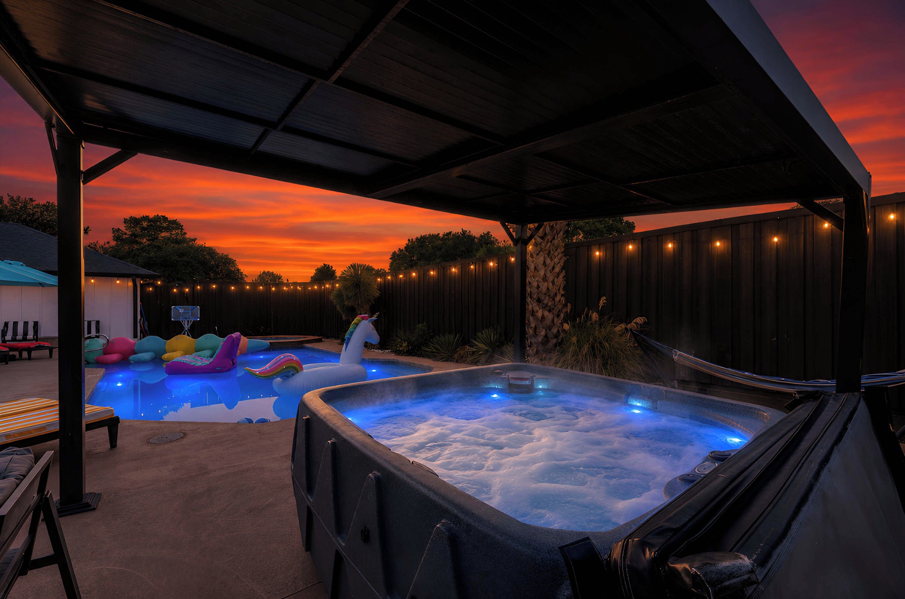 A hot tub with a wooden deck and a sunset in the background.