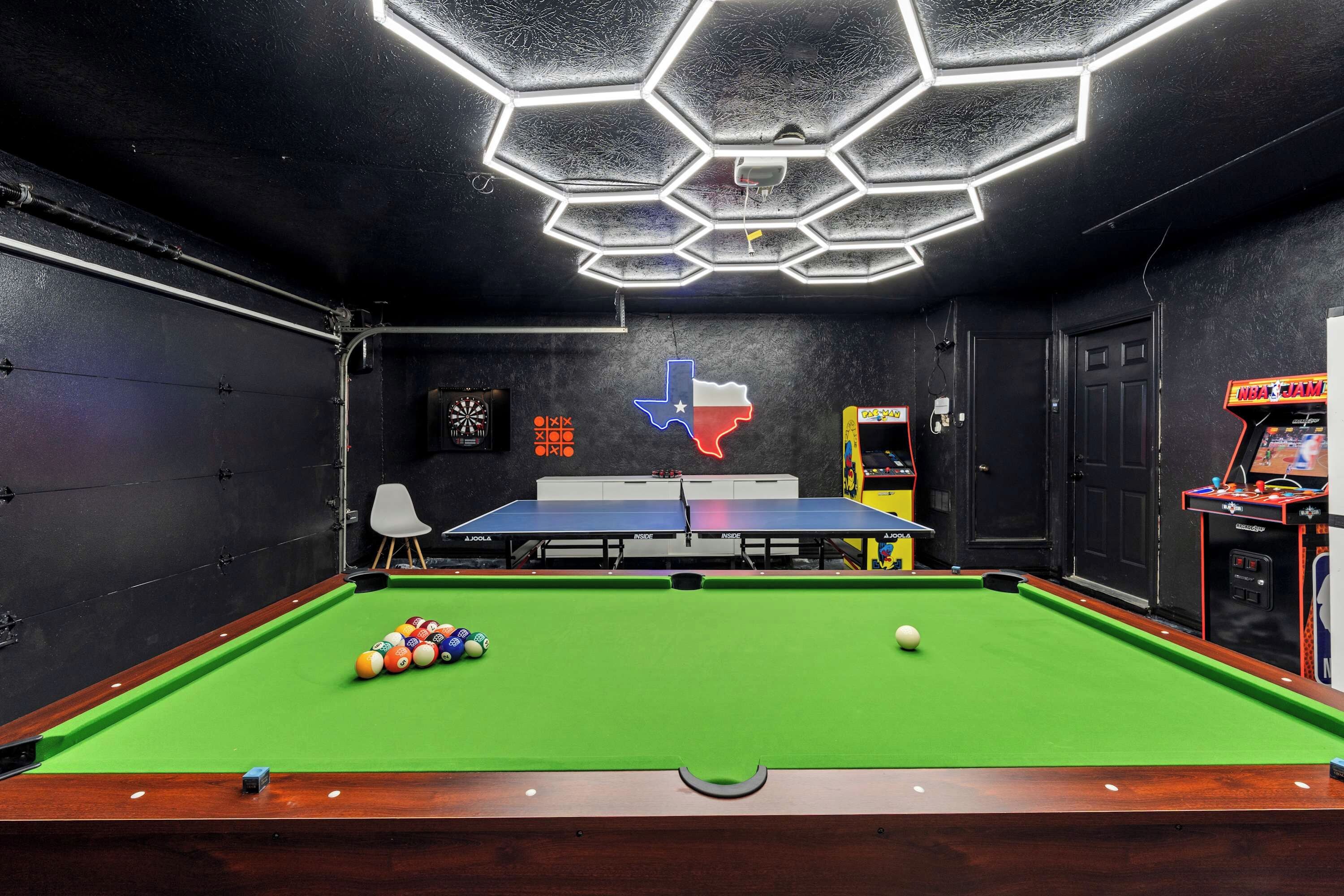 A billiards room with a pool table, a dartboard, and a Texas flag.