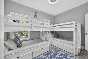 Ein Zimmer mit zwei Etagenbetten, einem Fenster mit Jalousien, einer Tür und einem gemusterten Teppich.