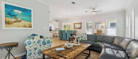 Ein Wohnzimmer mit einer Ledersofa, einem Holztisch und einem Sessel mit Blumenmuster.