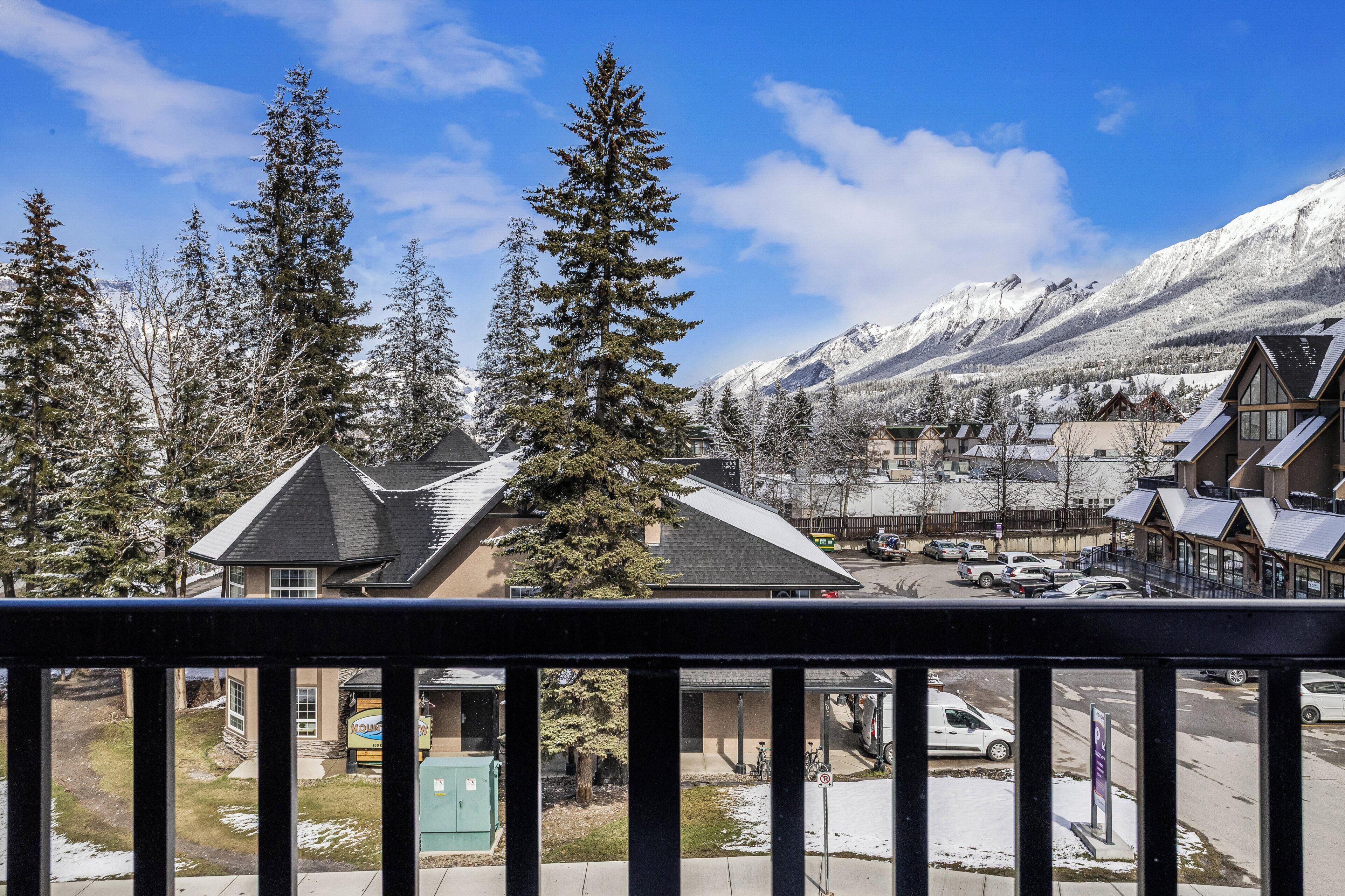 Un quartier résidentiel avec des maisons enneigées et une chaîne de montagnes en arrière-plan.