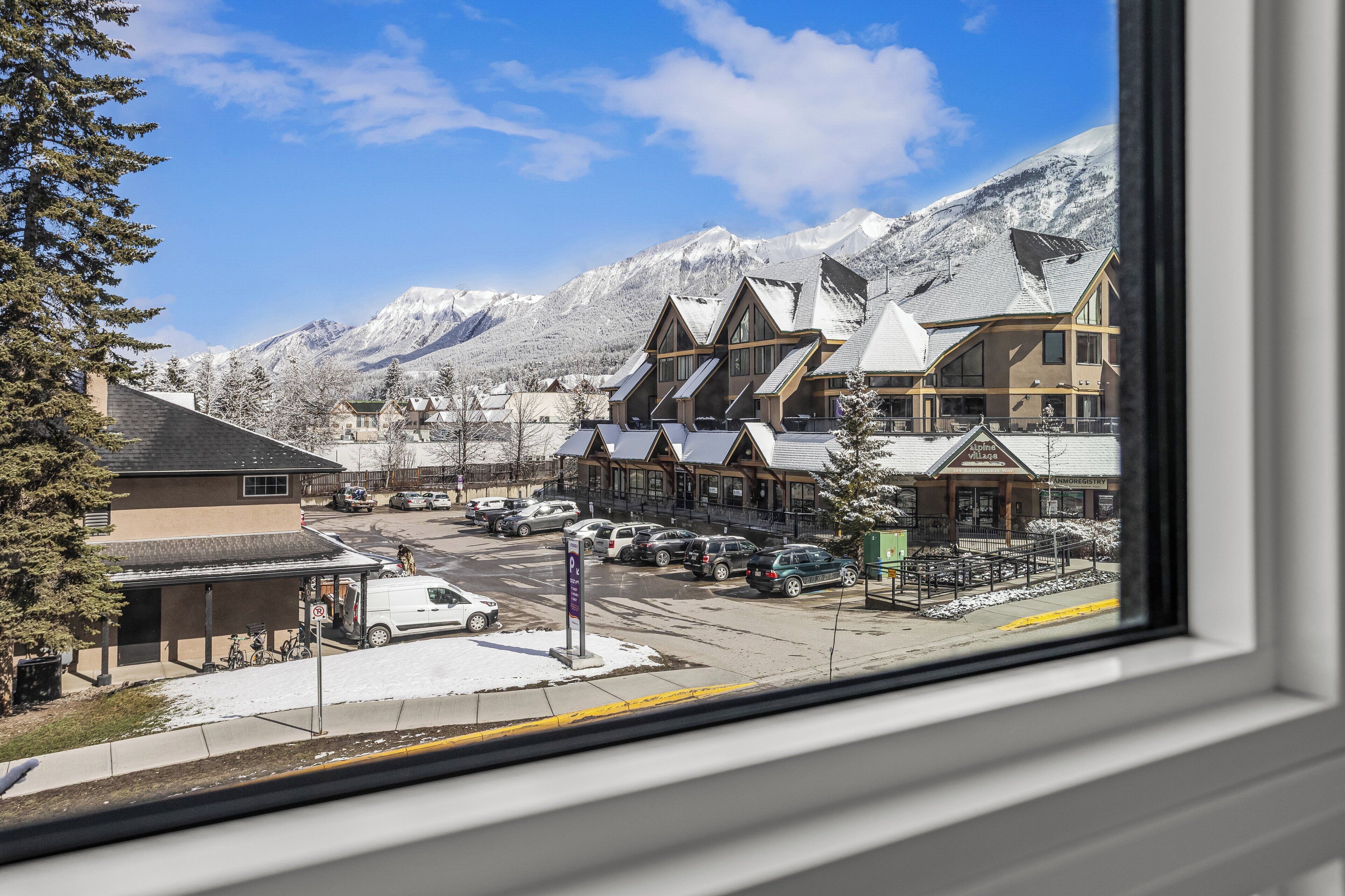 Une ville avec des bâtiments, un parking et, au loin, des montagnes enneigées.