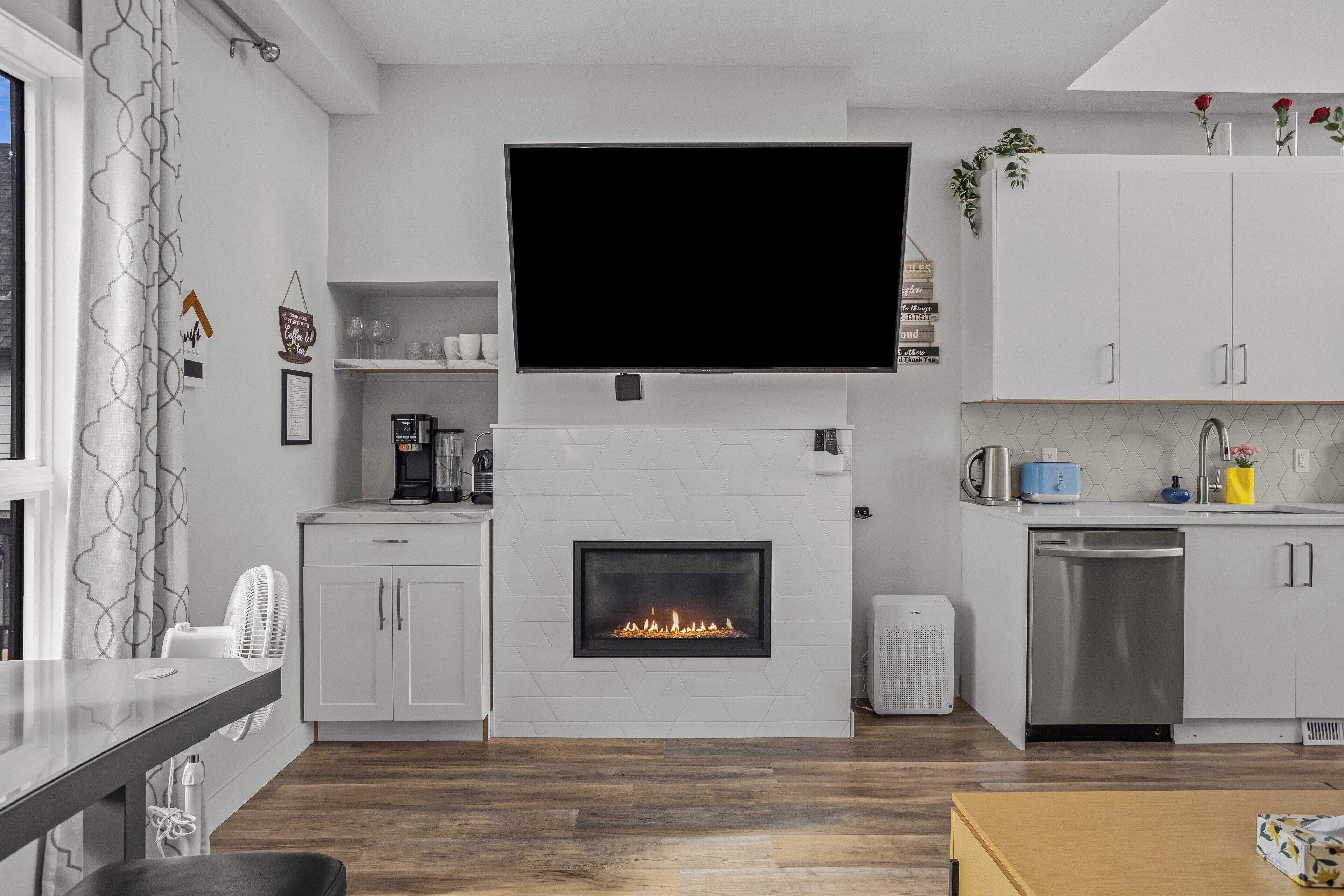 Eine moderne Küche mit integriertem Kamin, einem Flachbildfernseher und einer Kaffeemaschine.