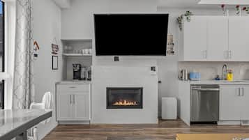 Eine moderne Küche mit integriertem Kamin, einem Flachbildfernseher und einer Kaffeemaschine.