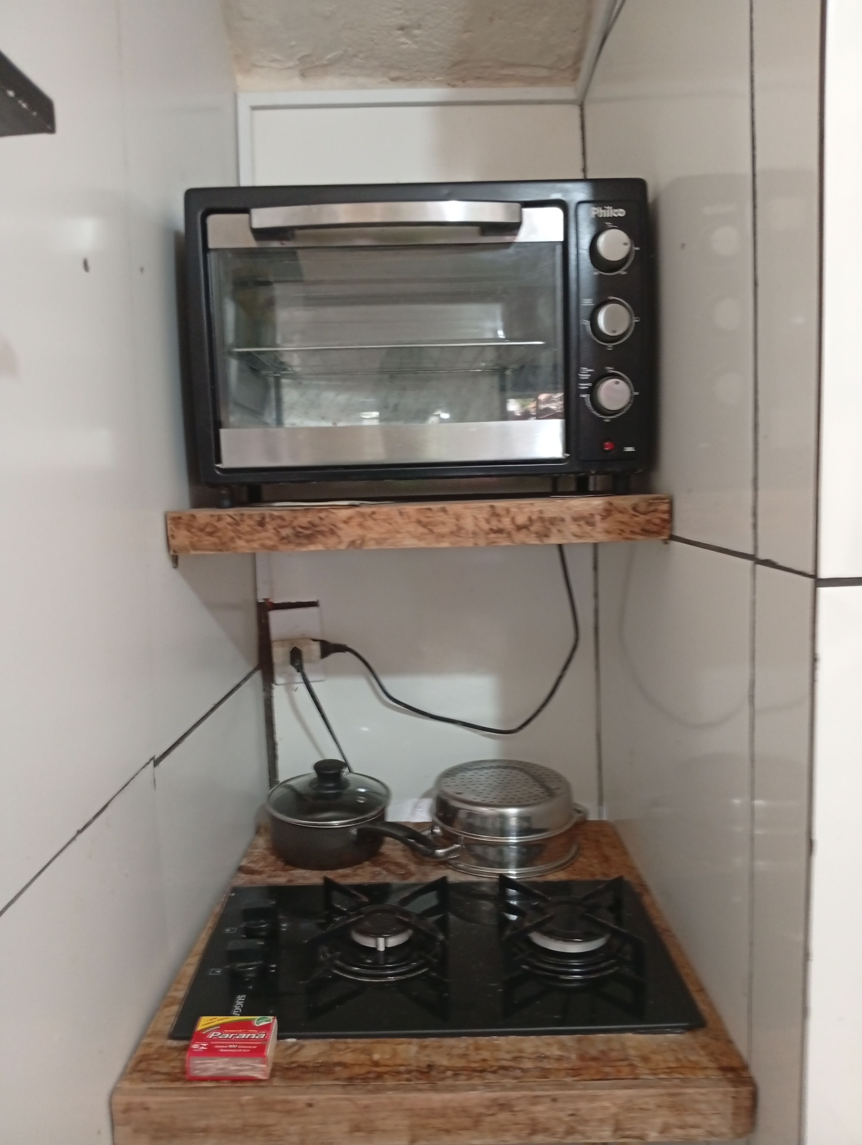 A kitchen with a built-in toaster oven, a gas stove, and a kettle on the countertop.