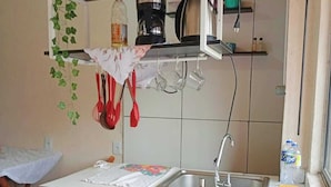 Eine Küche mit Ziegelrückwand, Spüle und einer Arbeitsplatte mit einem blumigen Tischläufer.