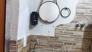 Ein Badezimmer mit einem Glaswaschbecken, einem Spiegel, einem Handtuchhalter und einer Toilette.