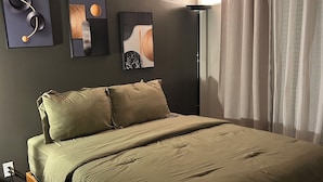 Un dormitori amb un llit, una tauleta de nit, una làmpada i decoració mural.
