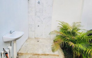 Un bagno con un lavandino bianco, una doccia e un piccolo gradino che conduce alla doccia.