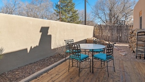 A patio with a round table and four chairs, a wooden deck, a low wall, and a wooden fence in the background. - Ideal location, Kiva Fireplace, 2 Bedroom, 2 Bathroom with parking! (Santa Fe)