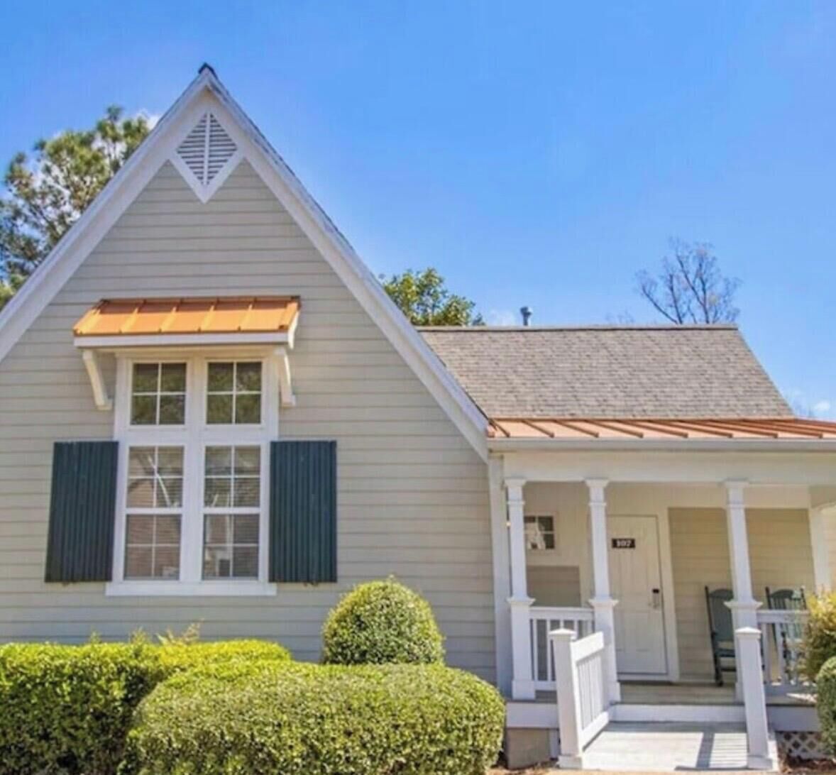 A single-story house with a gabled roof, a front porch with white railings, and a door marked with the number 307.