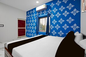 A bedroom with a bed, a window with a view, and an air conditioning unit. - Deluxe Jyoti Inn (Ali)