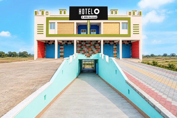 A hotel with a central entrance, a signboard, and a clear sky. - Deluxe Jyoti Inn (Ali)