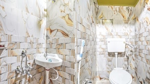 Ein Badezimmer mit Wänden im Marmor-Look, einem weißen Waschbecken und einer Toilette.