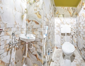 Ein Badezimmer mit Wänden im Marmor-Look, einem weißen Waschbecken und einer Toilette.
