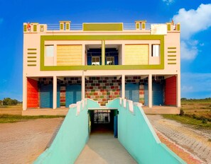 Ein zweistöckiges Gebäude mit einer zentralen Treppe, die zu einem überdachten Eingang führt.