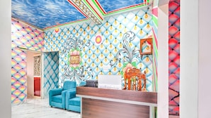 Ein Zimmer mit einem gemusterten Decken, einem blauen Sofa, einem hölzernen Empfangstresen und einer Wandverzierung.