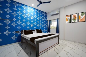 A bedroom with a bed, a ceiling fan, an air conditioning unit, and a window with curtains. - Deluxe Jyoti Inn (Ali)
