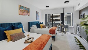 Una habitación de hotel moderna con dos camas, un comedor y una kitchenette.