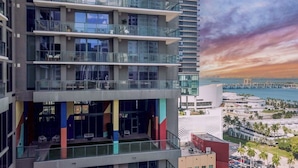 Un edificio de varios pisos con balcones y vistas a la costa, donde se puede ver un puente.