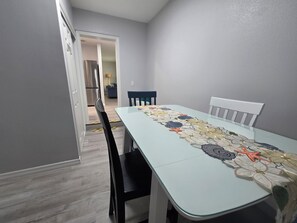 A dining area with a table set for four, chairs, and a kitchen in the background. - Seaside Village 2. 3 minutes to Anna Maria Island. Boat, Jetsky and Rv parking (Bradenton)