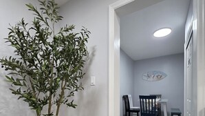 Ein Flur mit einem Blumentopf, ein Essbereich mit Stühlen und einem Tisch sowie ein 'Nichtraucher'-Schild an der Wand.