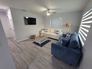 A modern living room with a sofa, coffee table, and a television mounted on the wall. - Seaside Village 2. 3 minutes to Anna Maria Island. Boat, Jetsky and Rv parking (Bradenton)