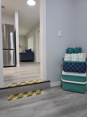 A hallway with a refrigerator, a sofa, and a trash bin. - Seaside Village 2. 3 minutes to Anna Maria Island. Boat, Jetsky and Rv parking (Bradenton)