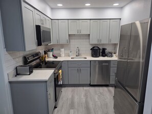 A modern kitchen with grey cabinets, stainless steel appliances, and a central island with a sink. - Seaside Village 2. 3 minutes to Anna Maria Island. Boat, Jetsky and Rv parking (Bradenton)
