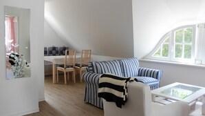 Ein modernes Wohnzimmer mit einer Couch, Sesseln, einem Couchtisch und einem Fenster.