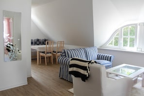 Uma sala de estar moderna com um sofá, poltronas, uma mesa de centro e uma janela.