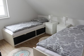 Quarto com cama, mesa de cabeceira e cómoda.