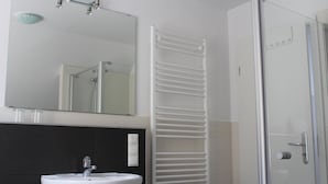 Ein Badezimmer mit einem weißen Waschbecken, einem Spiegel und einer Glasdusche.