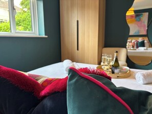 Et hotelværelse med en seng, et træskab, et vindue med udsigt og et bord med en flaske og glas.