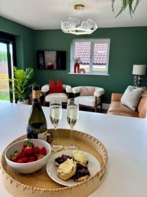A dining table with a bottle of wine, glasses, and a plate with food. - 2bed Modern Home Garden Off Road Parking (Bath and North East Somerset)