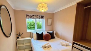 Quarto com cama, mesas de cabeceira, janela e luminária no teto.