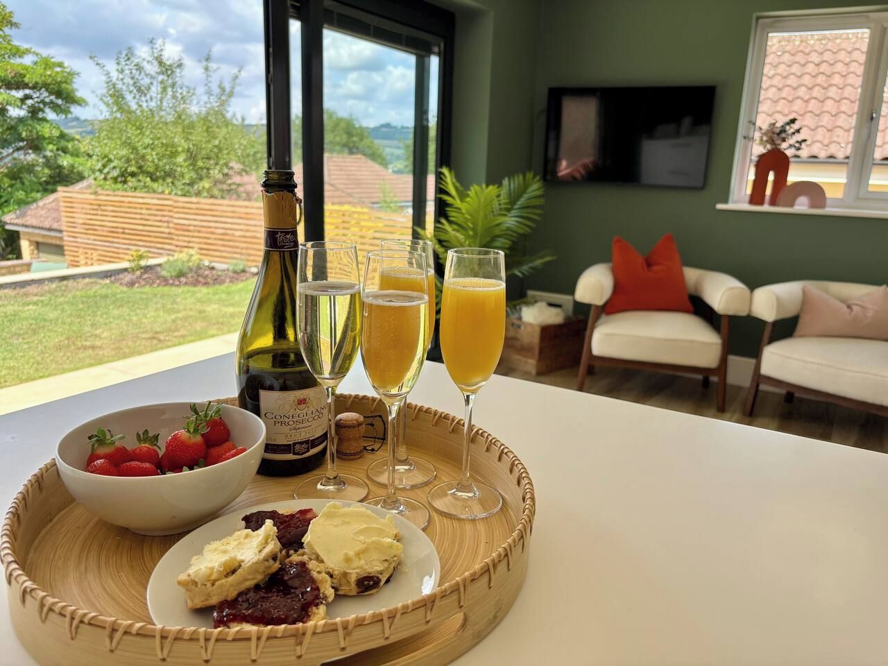 A dining table with a bottle of wine, glasses of juice, and a bowl of strawberries.