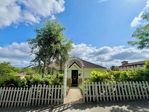 A small building with a tiled roof, surrounded by a white picket fence, and a clear sky above. - 2bed Modern Home Garden Off Road Parking (Bath and North East Somerset)