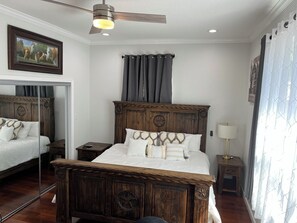 A bedroom with a large bed, a ceiling fan, a nightstand, a bedside table, and a window with curtains. - Texas Style historic / modern spacious home near Downtown (San Antonio)
