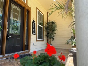 A building entrance with a dark door, two windows, a 'WELCOME' sign, and potted plants. - Texas Style historic / modern spacious home near Downtown (San Antonio)