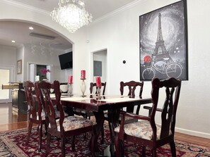 A dining area with a chandelier, a large painting of the Eiffel Tower, and a red carpet. - Texas Style historic / modern spacious home near Downtown (San Antonio)