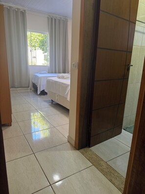 A room with a bed, a window with curtains, and a tiled floor. - Charming 2-bedroom house in serene Foz do Iguaçu with AC (Foz do Iguaçu)
