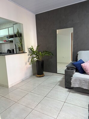 A modern living space with a kitchen area, a large mirror, and a seating area with cushions. - Charming 2-bedroom house in serene Foz do Iguaçu with AC (Foz do Iguaçu)