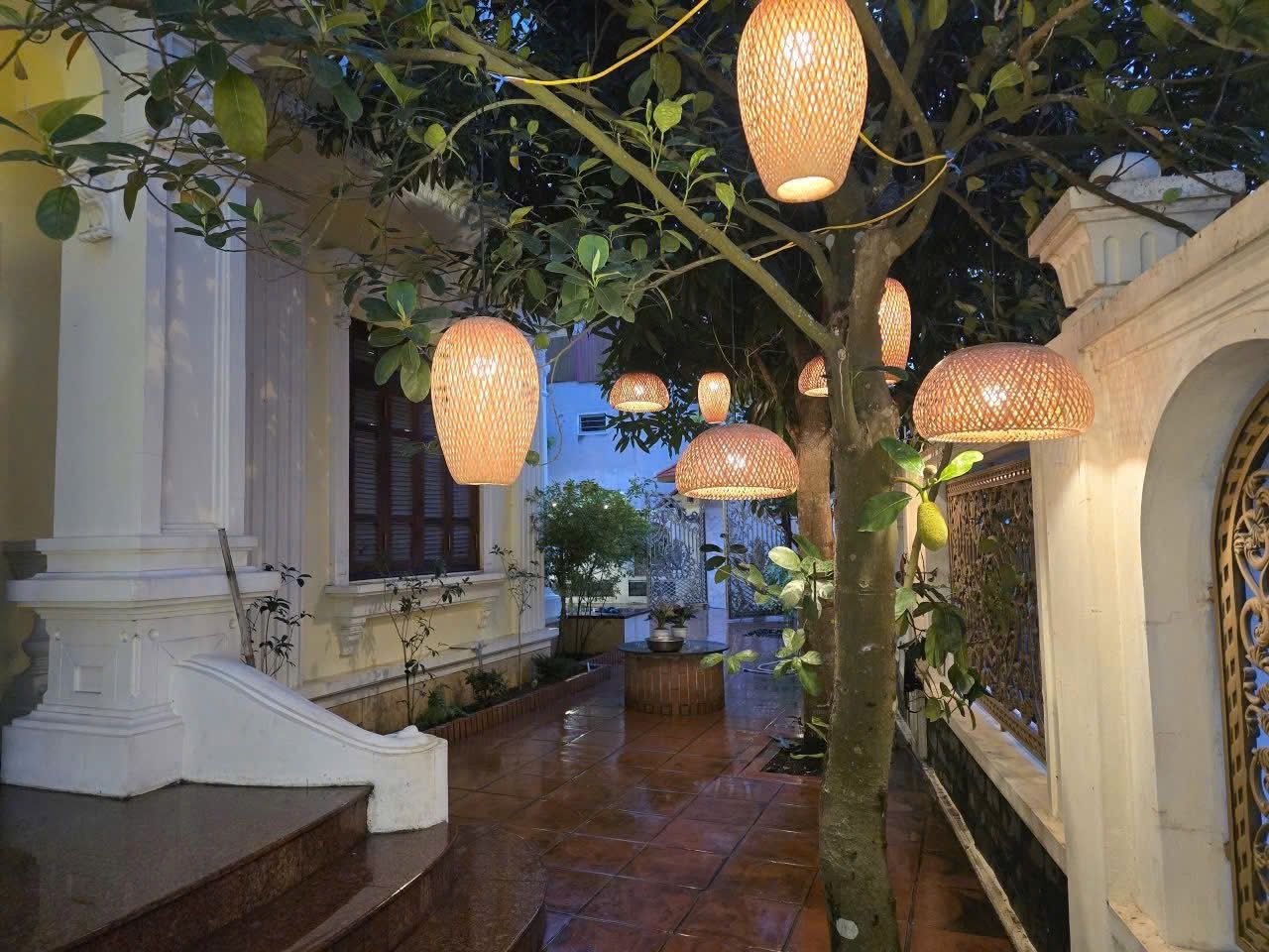A corridor with hanging lanterns, a tree, and classical architecture.