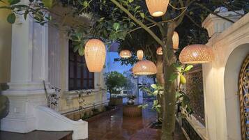 A corridor with hanging lanterns, a tree, and classical architecture.