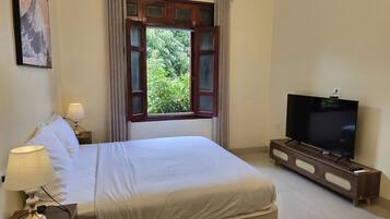 Ein Hotelzimmer mit Bett, Fernseher, Lampe und einem Vorhangfenster.