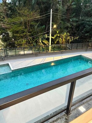 A rectangular swimming pool with a tiled edge, surrounded by a black metal railing. - Brand new apartment. with complete leisure in the center (Ubatuba)